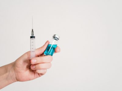 pexels-photo-3952241-3952241 Hand holding a syringe and vaccine vial on a white background, symbolizing healthcare and immunization.