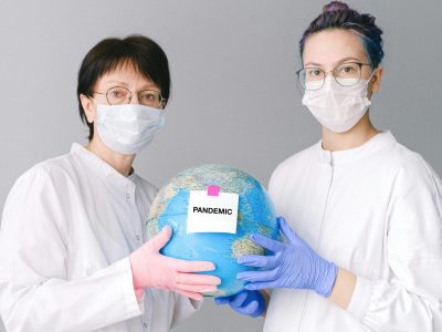 pexels-photo-4167561-4167561 Two healthcare professionals in masks hold a globe labeled 'Pandemic,' symbolizing global healthcare crisis.